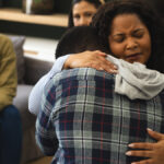 women intensely hugging a fellow member in detox meeting