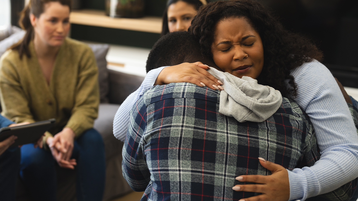 women intensely hugging a fellow member in detox meeting